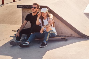 Genç trend çiftimiz güneşli parklarda uzun kaykaylarıyla oturuyorlar.