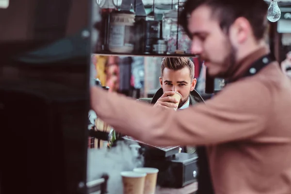 Красивый ухоженный мужчина наслаждается кофе, сидя в кафе — стоковое фото