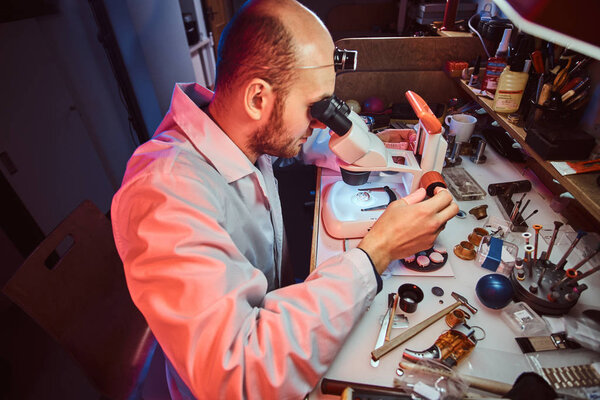 Serious watchmaker  is repairing cutomers order at his own repairing studio