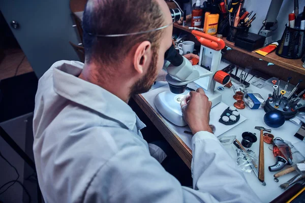 Seriöser Uhrmacher repariert Bestecke in seinem eigenen Reparaturatelier — Stockfoto