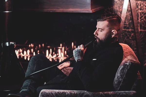 Красивий бородатий чоловік розслабляється в лаунжі під час куріння кальяну — стокове фото