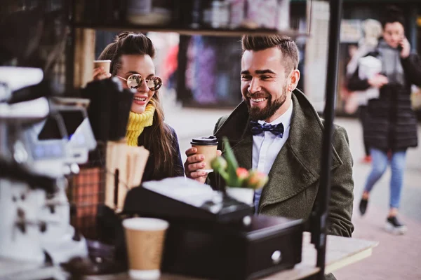 Atractiva pareja inteligente está disfrutando del café mientras se sienta afuera en el pequeño coffeesho — Foto de Stock