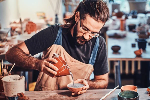 Diligente hombre atractivo está poniendo arcilla colorida a su nueva olla hecha a mano . — Foto de Stock