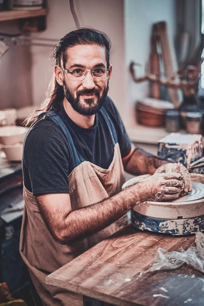 Atrakcyjny mężczyzna w okularach pracuje nad własnym projektem gliny. — Zdjęcie stockowe