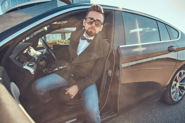 Güneş gözlüğü bakımlı modern adam otoparkta arabasında oturuyor. — Stok fotoğraf