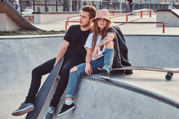 Unga attraktiva par studenter sitter på skatepark med sina longboards — Stockfoto