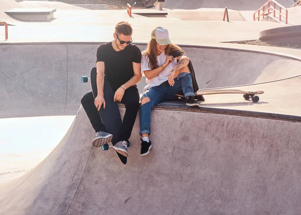 Glimlachend gelukkig paar studenten zitten in het Skatepark met hun longboards — Stockfoto