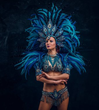 Güzel brasil dansçı ellerini haçlar duruyor. Mavi tüy kostümü giyiyor..