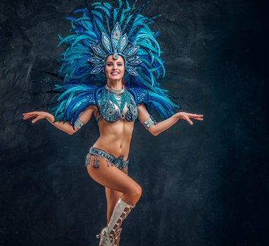 Güzel brasil dansçı ellerini haçlar duruyor. Mavi tüy kostümü giyiyor..