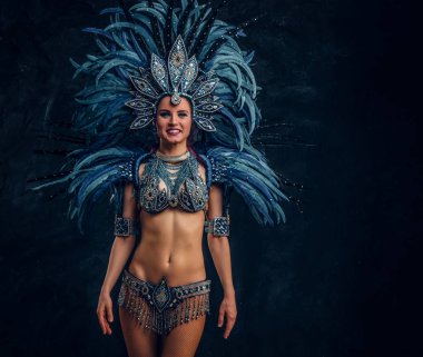 Mutlu dansçı fotoğrafçı için poz vermektir. Mavi tüy kostümü giyiyor..