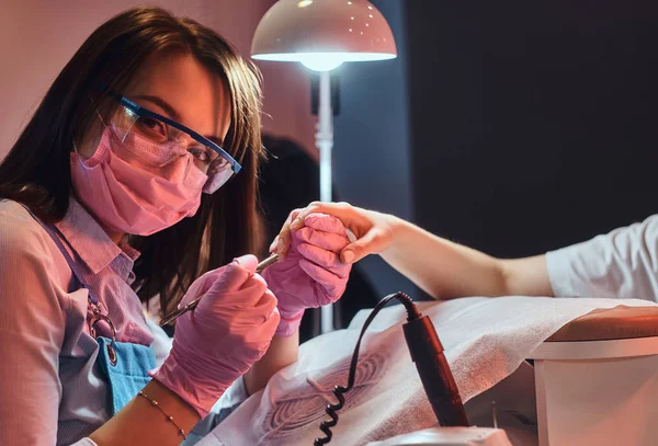 Alegre manicurista está mirando a la cámara mientras se trabaja en los clientes uñas . —  Fotos de Stock