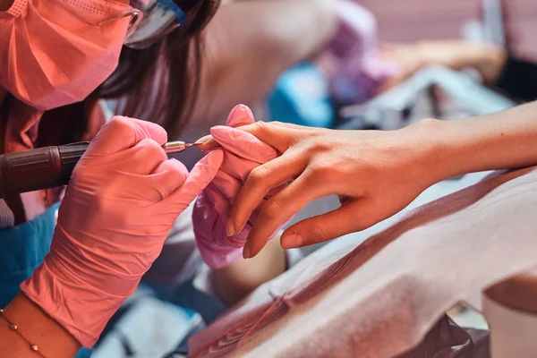 Diligente maestro de uñas enfocado está trabajando en clientes cuticule . —  Fotos de Stock