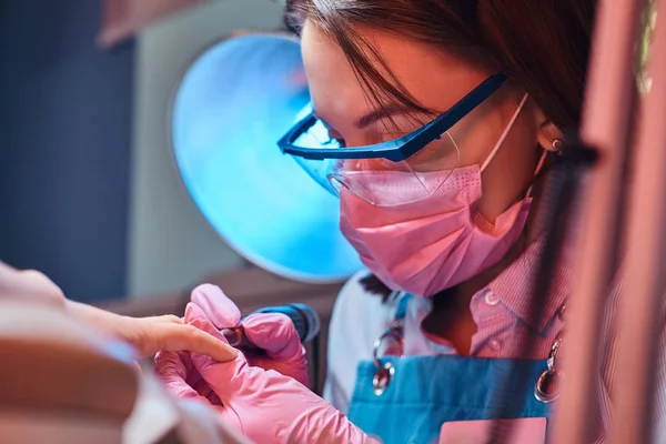 Focalizzato diligente manicure sta lavorando sul suo posto di lavoro al salone di manicure — Foto Stock