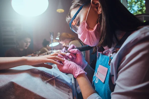 Skoncentrowany sumienny manicurysta pracuje w jej miejscu pracy w salonie manicure — Zdjęcie stockowe