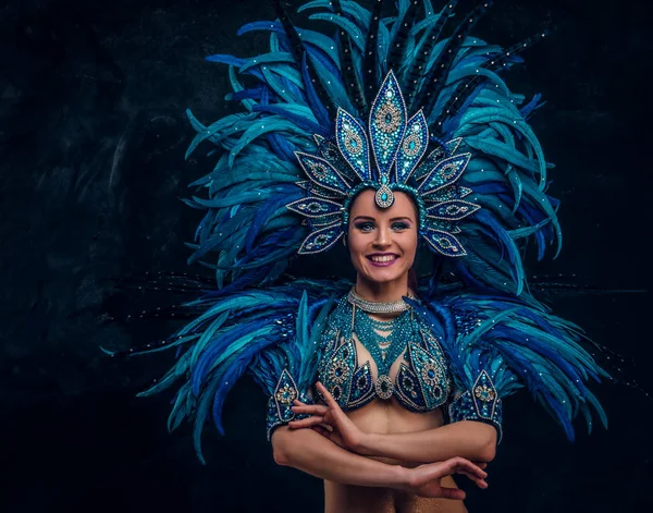 Die schöne brasilianische Tänzerin steht mit verschränkten Händen da. sie trägt ein Kostüm aus blauen Federn. — Stockfoto