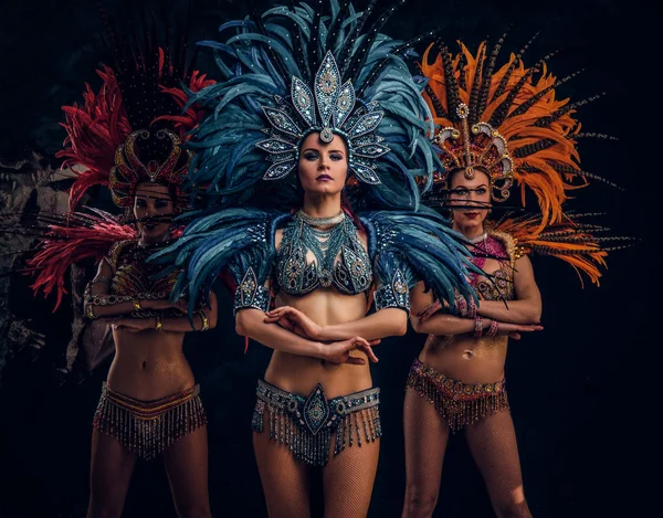 Drei schöne Frauen in traditionellen brasilianischen Karnevalskostümen posieren für Fotografen im Studio. — Stockfoto