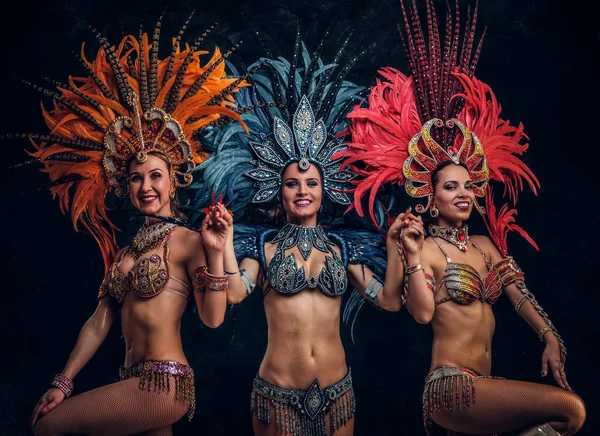 Drei schöne Frauen in traditionellen brasilianischen Karnevalskostümen posieren für Fotografen im Studio. — Stockfoto
