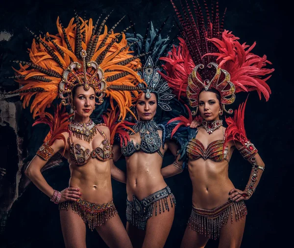 Trois belles femmes en costumes carnavals brésiliens traditionnels posent pour le photographe en studio . — Photo