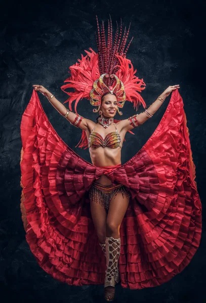Talentoso bailarín alegre en traje de plumas rojas está posando en un pequeño estudio oscuro . —  Fotos de Stock
