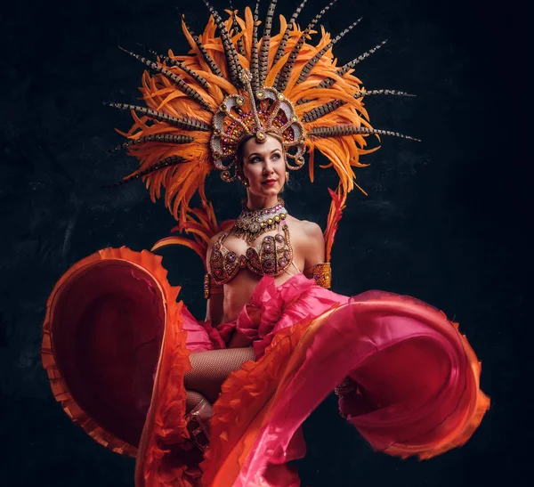 Talentuoso ballerino gioioso in costume di piuma rossa sta posando in un piccolo studio buio . — Foto Stock