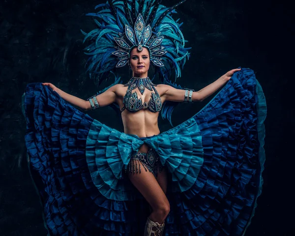 Talented joyful dancer in red feather costume is posing at small dark studio. — Stock Photo, Image