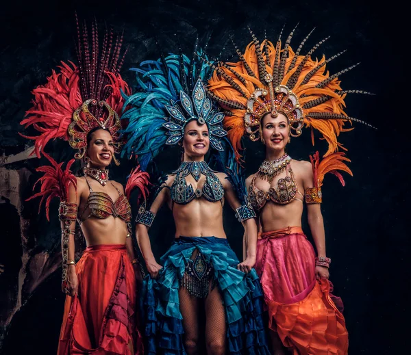 Trois belles femmes en costumes carnavals brésiliens traditionnels posent pour le photographe en studio . — Photo