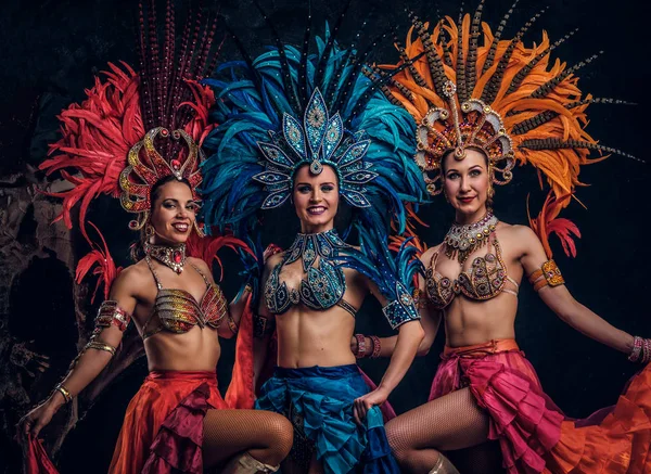 Trois belles femmes en costumes carnavals brésiliens traditionnels posent pour le photographe en studio . — Photo