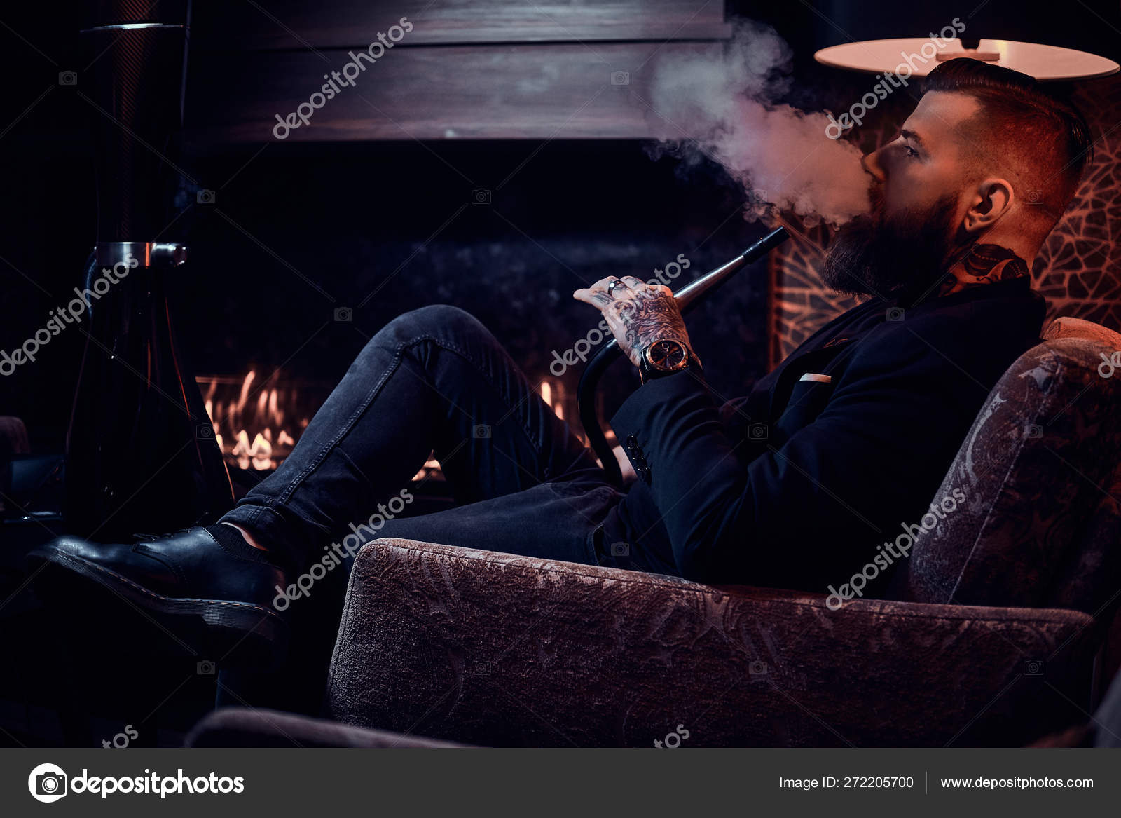 Bearded relaxed man is sitting on the armchair and smoking hookah near  fireplace — Stock Photo © fxquadro #272205700, image size:1600x1167