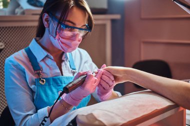 Genç manikürcü iş yerinde müşterisiyle çalışıyor..