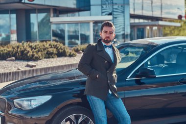 Bakımlı çekici adam park kendi araba üzerinde eğilerek