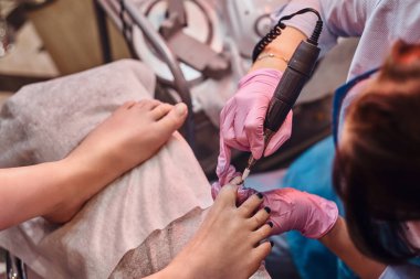 Genç, neşeli manikürcü pedikür stüdyosunda müşteriler üzerinde çalışıyor..