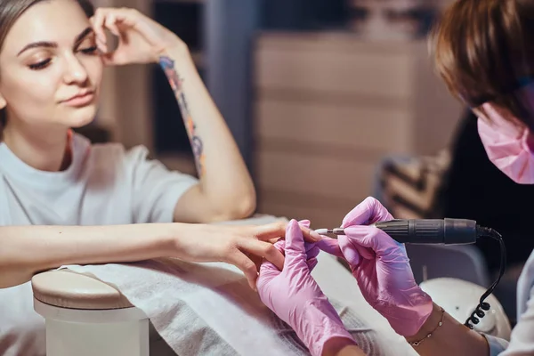 Mooie jonge vrouw resigerende manicure van meester. — Stockfoto