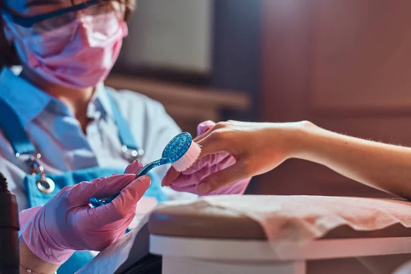 Junge Maniküre arbeitet an ihrem Arbeitsplatz mit Kunden. — Stockfoto