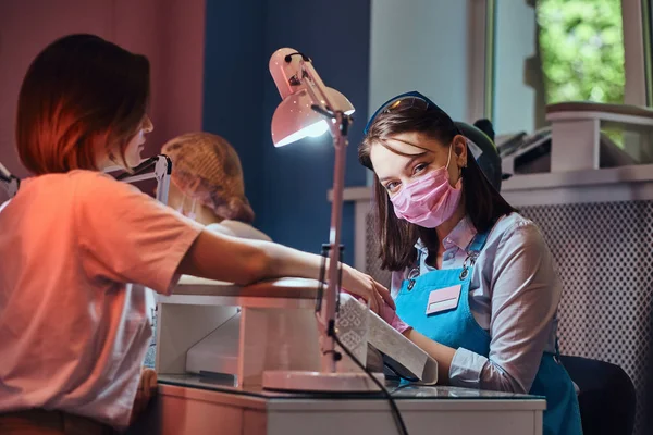 Joven manicura atractiva está haciendo cuidado de uñas para otra mujer — Foto de Stock