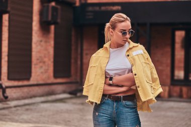 Güneş gözlüğü arsız trendy kadın rastgele şehir bahçesinde fotoğrafçı için poz.