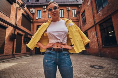 Simetrik bahçesinde güneş gözlüğü ve denim güzel kadın düşük açılı fotoğraf.