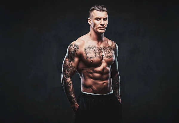 Egy izmos tetovált férfi egy sötét háttér. — Stock Fotó