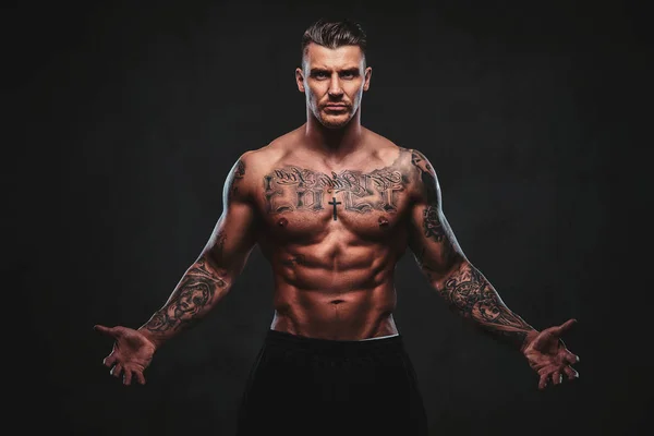 Egy izmos tetovált férfi egy sötét háttér. — Stock Fotó