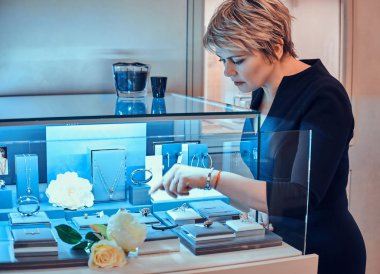 Mağaza asistanı kuyumcuda çiçeklerle sergilenen güzel mücevher yeni süslemeler çeşitli koymak