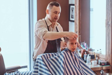 Küçük sevimli çocuk moda kuaför salonunda expirienced berber trendy saç kesimi oluyor
