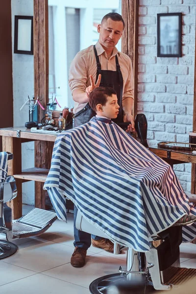 Small pretty school boy had his first trendy haircut at modern barbershop. — Stock Photo, Image