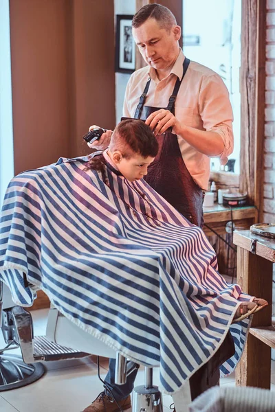 Pequeño niño de la escuela tenía su primer corte de pelo de moda en la barbería moderna . — Foto de Stock