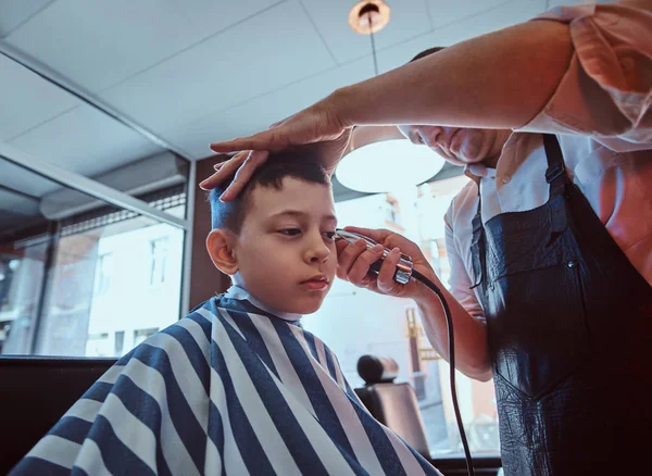 Small school boy had his first trendy haircut at modern barbershop. — Stock Photo, Image