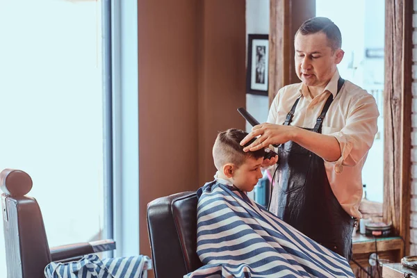 Kis iskolás fiú egyre trendi fodrász a expirienced Borbély a modern Barbershop — Stock Fotó