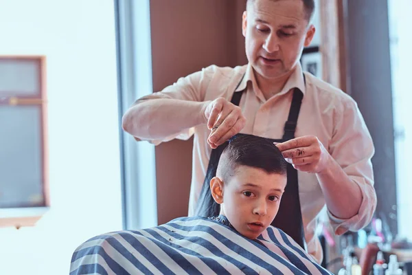 Liten skol pojke hade sin första trendiga frisyr på modern barbershop. — Stockfoto