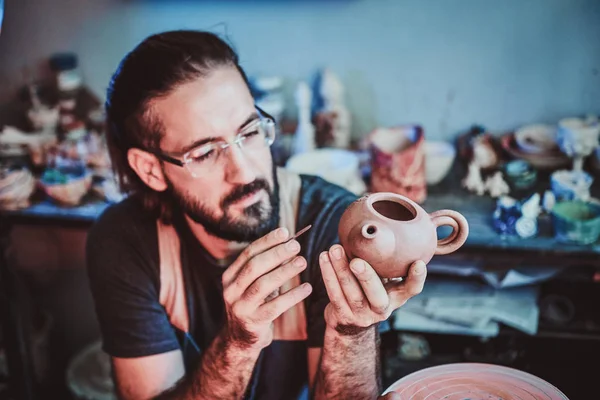 Гончар в окулярах на своїй майстерні працює на новому чайнику ручної роботи . — стокове фото
