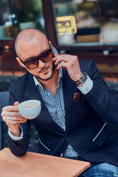 Serious hombre exitoso está llamando por móvil y disfrutando de su café . —  Fotos de Stock