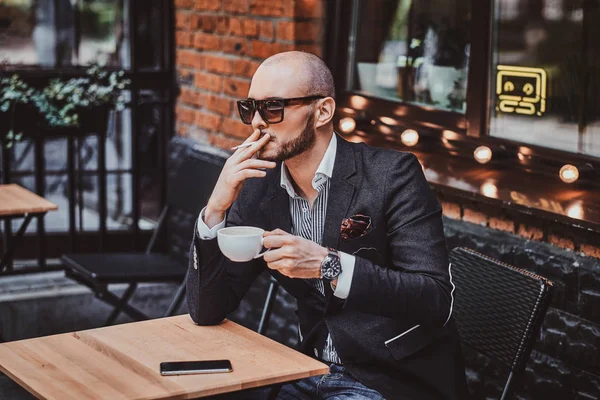 El hombre pensativo está tomando café y fumando fuera de la cafetería —  Fotos de Stock