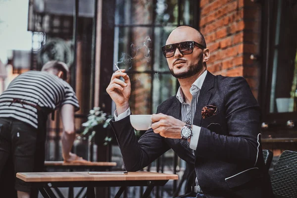 El hombre pensativo está tomando café y fumando fuera de la cafetería — Foto de Stock