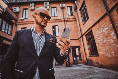 Güneş gözlüğü takan adam cep telefonuyla sohbet ediyor